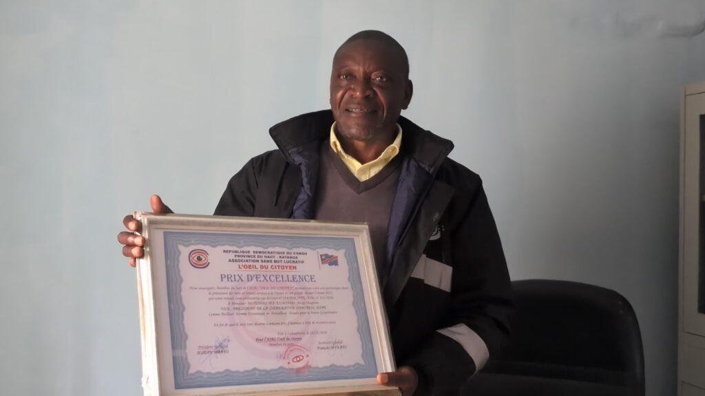 Alexis Mutombo, Vice-président de COMIAKOL, présentant son Prix d’excellence décerné par l’ASBL l’œil du citoyen